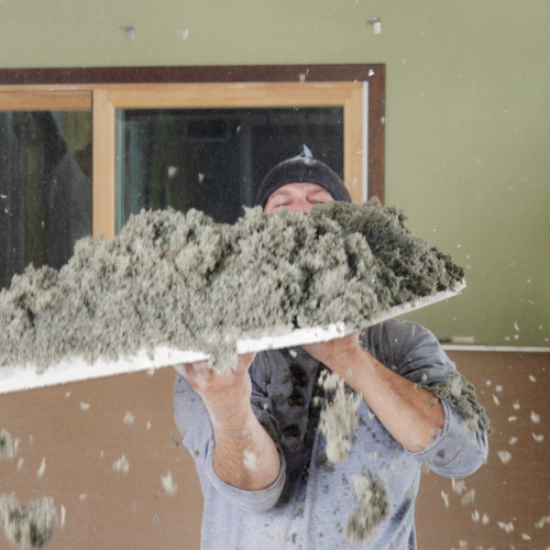worker holding a part of the ceiling with cellulose insulation